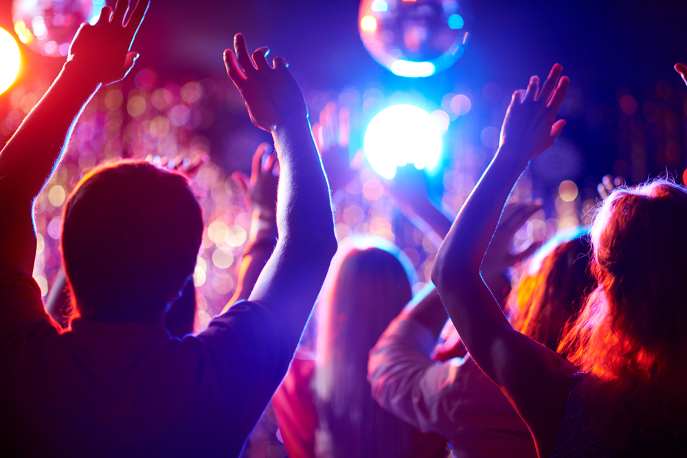 A group of people waving their arms in a dance club
